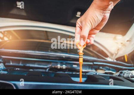 Der Mechaniker zieht den Messstab im Motorraum, um den Ölstand zu überprüfen, Auto-Wartung Service-Konzept Stockfoto