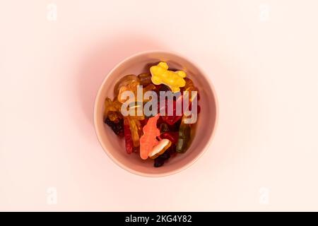 Bunte Gummibonbons in einem pinkfarbenen Becher auf pinkfarbenem Hintergrund Stockfoto