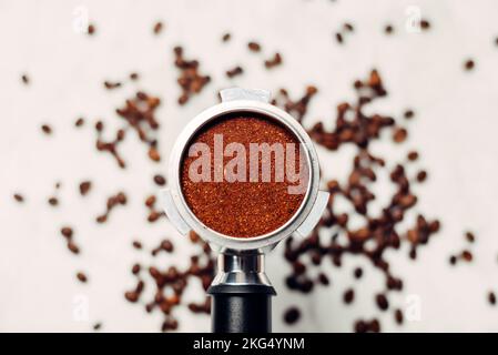 Portafilter mit gemahlenem Kaffee auf hellgrauem Hintergrund. Der Blick von oben. Stockfoto