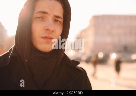 Ein trauriger Teenager mit Kapuze, der im Winter in der Stadt steht Stockfoto