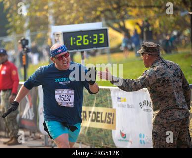 Eric Ring, ein Teilnehmer am Marine Corps Marathon 47. 10K, hat ein US-Marine hoch gestellt, als er die Ziellinie für den 47. MCM10K, Arlington, Virginia, überquert, 30. Oktober 2022. Die MCM10K wird am selben Tag wie der Marine Corps Marathon veranstaltet, wobei der Start des Rennens in der National Mall erfolgt. Läufer aller Niveaus nahmen an der MCM10K Teil; dieser spezielle Kurs bot MCM-Handradlern linke Fahrspuren mit den Polizeieskorts. Stockfoto