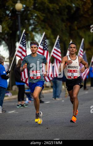 Tyler O. Cooper, Teilnehmer am Marine Corps Marathon 47., Left, und der US Marine Corps Capt. Dylan M. Villescas, ein All-Marine-Läufer, Rechts, laufen durch die „Wear Blue: Run to Remember“-Meile in Hains Point, Washington, D.C., 30. Oktober 2022. Der legendäre Kursabschnitt ist eine Hommage an die Menschen, die ihr Leben für dieses Land hingegeben haben, mit 225 Postern mit Fotos der Gesichter der Gefallenen. Stockfoto