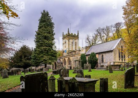 Blick auf die St. Lawrence's Kirche und den Kirchenhof im Herbst, Eyam, Peak District, England Stockfoto