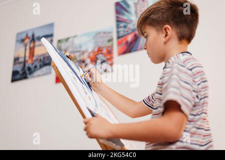 Der Junge malte das Bild mit Pinsel und Farbe. Stockfoto