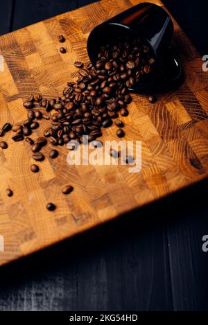 Kaffeebohnen auf Holzbrett verstreut. Hintergrund für Kaffee Stockfoto