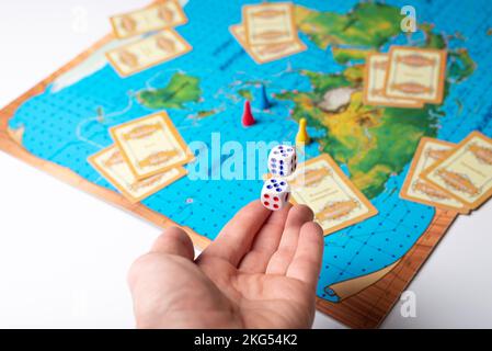 Die Hand würfelt mit Zahlen auf dem Brettspiel Stockfoto