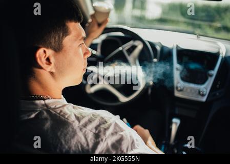 Ein Typ raucht während der Fahrt in einem Auto Stockfoto