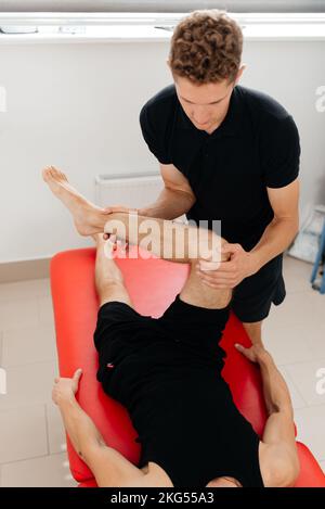 Sportmassage. Der Masseur arbeitet mit dem Patienten zusammen und massiert die Reabilitation Stockfoto