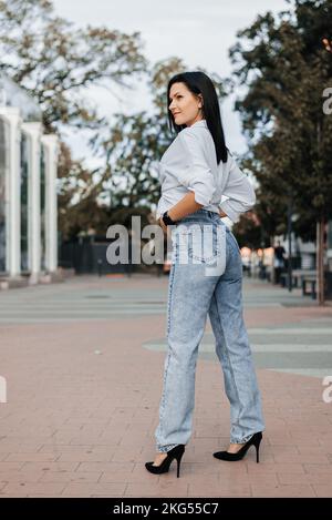 Junge, stilvolle oder traitsche Frau in Jeans auf der Straße Stockfoto