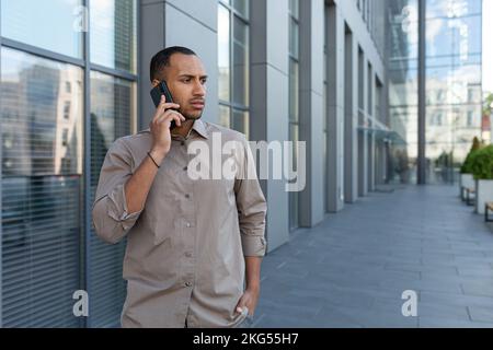 Besorgter und aufgebrachter junger Spanier. Ein Afroamerikaner steht auf der Straße, spricht am Telefon, sieht weg. Stockfoto