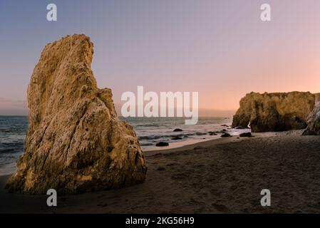 Große Felsen am El Matador Beach Malibu mit Wellen, die die Küste während des Sonnenuntergangs waschen Stockfoto