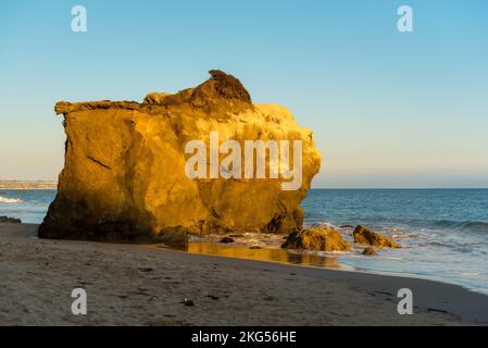 Große Felsen am El Matador Beach Malibu mit Wellen, die die Küste während des Sonnenuntergangs waschen Stockfoto