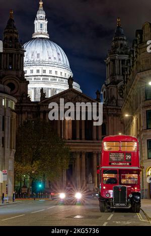 Der klassische alte Doppeldeckerbus aus London parkte nachts am Ludgate Hill in London mit der beleuchteten weißen Kuppel der St Paul's Cathedral Stockfoto