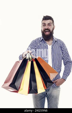 Tolle Auswahl, tolle Einkäufe. Glücklicher Hipster, der Einkäufe in Papiertaschen auf Weiß hält. Ein brutaler bärtiger Mann, der mit Modekäufen lächelt Stockfoto