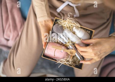 Weibliche Hände halten Weihnachtsgeschenke voller Schönheit Geschenke für Haut-, Körper- und Gesichtspflege Stockfoto