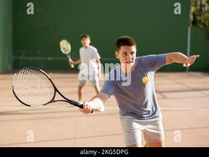 Junger männlicher Pelotaspieler trifft Ball mit Schläger Stockfoto