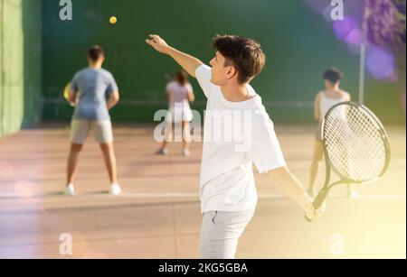 Junger männlicher Pelotaspieler trifft Ball mit Schläger Stockfoto