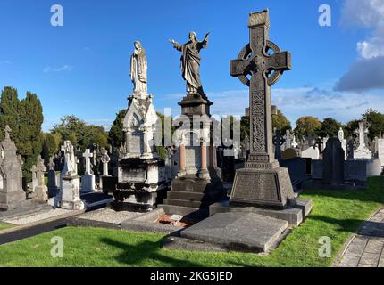 Dublin, Irland. 5. Oktober 2022. 20221005 - geschnitzte Figuren der Jungfrau Maria und Jesu Christi und ein keltisches Kreuz zieren Gräber auf dem Friedhof von Glasnevin in Dublin, Irland. (Bild: © Chuck Myers/ZUMA Press Wire) Stockfoto