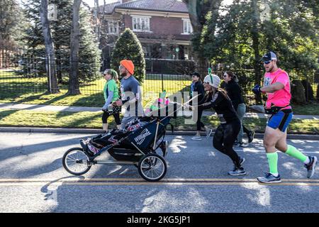3-16-2019 Tulsa USA - Gruppe kostümierter Läufer bei der St. Patricks Day Parade, die eine behinderte Person drängen, damit sie das Erlebnis mit dem verschwommenen Haus genießen kann Stockfoto