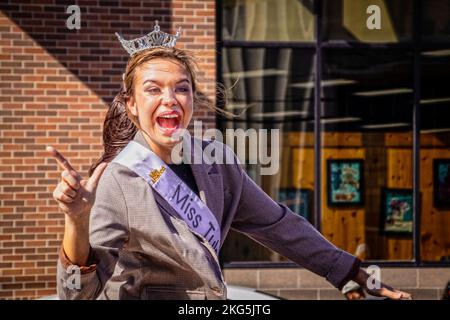 10-22-2022 Tulsa USA - ein wunderschönes Mädchen, das bei der Halloween-Parade den Miss Tulsa-Wettbewerb gewonnen hat, mit einem großen Lächeln, während sie das Go Pokes-Schild überreicht Stockfoto