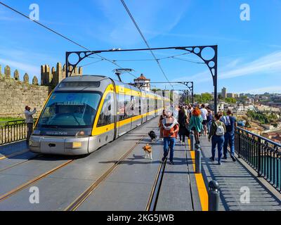 PORTO, PORTUGAL - 15. APRIL 2022: Menschen, die mit Hunden an der Dom Luis Brücke spazieren, Touristenmassen, U-Bahn, Sonnentag Stockfoto