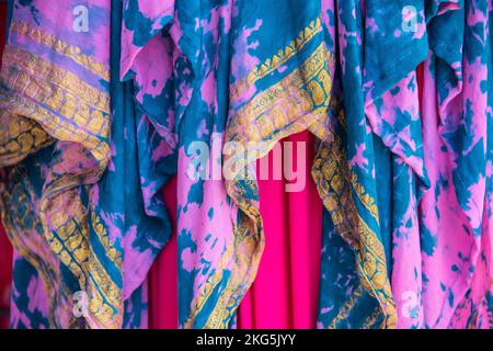 Hintergrund: Farbenfrohe drapierte, überlappende Stoffe in Rosa und Türkis mit goldgelber Stickerei - Bo- oder Zigeuner-Look Stockfoto