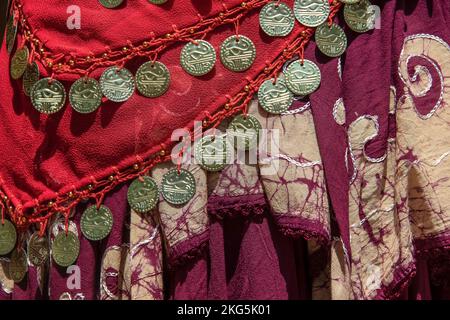 Hintergrund mit Zigeunerschals mit dekorativen Münzen und Perlen sowie markantem Webstoff für jedes Stück - rot und burgunderrot mit Batik und Stockfoto