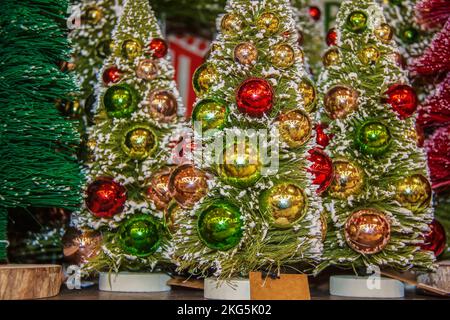 Hintergrund von Miniatur beflockte Weihnachtsbäume mit glänzenden runden Ornamenten - selektiver Fokus auf den Vordergrund Stockfoto