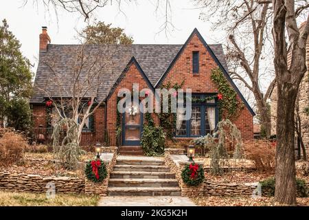 Cute Brick Cottage mit rote Schleifen und viel Grün - für Weihnachten in trostlosen Winter eingerichtet Stockfoto