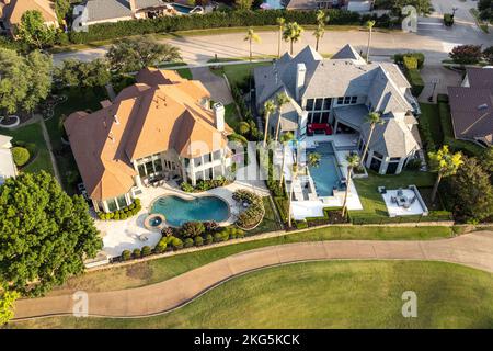 Luftdrohne Ansicht von Luxusvillen mit Swimmingpools umgeben von grünem Gras und Bäumen im Sommer. Stockfoto