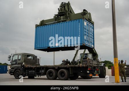 Ein US Marine mit Combat Logistics Regiment 37, 3. Marine Logistics Group, nutzt einen Kalmar RT240 Container Handler für unwegsames Gelände, um während der Vorbereitungen für einen bilateralen Konvoi während des Keen Sword, in Camp Kinser, Okinawa, Japan, 15. November, einen japanischen Transportcontainer auf ein Fahrzeug der japanischen Selbstverteidigungskräfte zu schleppen. 2022. Keen Sword übt die kombinierten Fähigkeiten und die Letalität aus, die zwischen dem 1. Marine Aircraft Wing, der III Marine Expeditionary Force und der Japan Self Defense Force (JSDF) entwickelt wurden. Diese bilaterale Übung im Feldtraining zwischen dem US-Militär und JSDF stärkt die Interoperabi Stockfoto