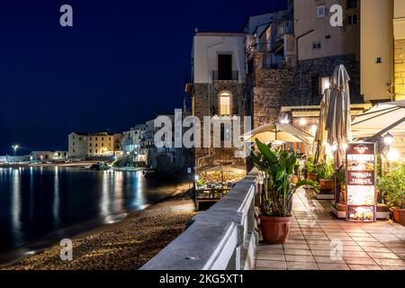 Ein Restaurant am Meer bei Nacht, Cefalu, Sizilien, Italien. Stockfoto