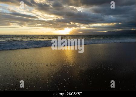 Ein Sonnenuntergang Am Meer Mit Sonnenstrahlen, Die Hinter Den Wolken Ausstrahlen Stockfoto