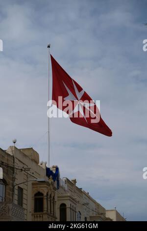 Eine vertikale Aufnahme der großen maltesischen Flagge, die über einem Regierungsgebäude winkt Stockfoto