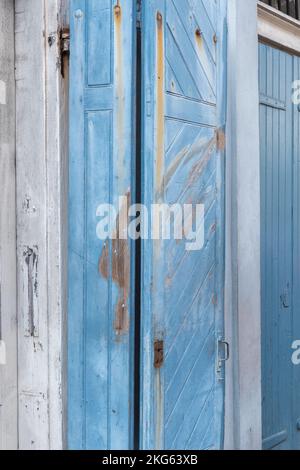 Die Fensterläden aus verblasstem Holz sind in einem weichen Blau gestrichen. Stockfoto