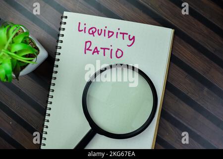Das Konzept des Liquiditätskoeffizienten schreibt auf ein Buch isoliert auf einem Holztisch. Stockfoto