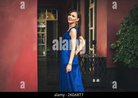 Hübsches asiatisches Model in blauem Kleid, das sich in einer üppigen Inneneinrichtung posiert Stockfoto