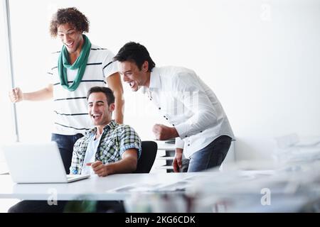 Das ist urkomisch. Drei männliche Mitarbeiter, die zusammen im Büro arbeiten. Stockfoto