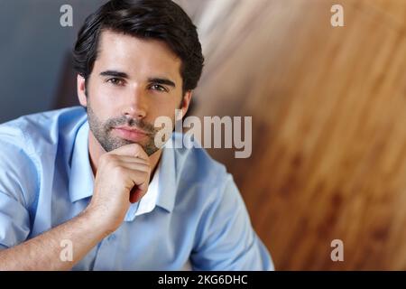 Ich bin geschäftlich sehr ernst. Nahaufnahme eines gutaussehenden Geschäftsmannes mit der Hand auf dem Kinn. Stockfoto