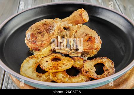 Hähnchenschenkel mit Pilzen und Apfeltassen im Ofen gebacken. Hühnchen in Apfelwein. Stockfoto