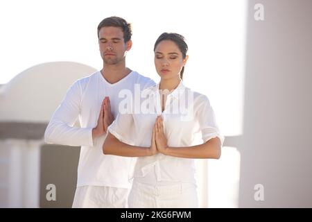 Partner geistig körperlich und geistig. Ein junger Mann und eine junge Frau, die im Freien Yoga machen. Stockfoto