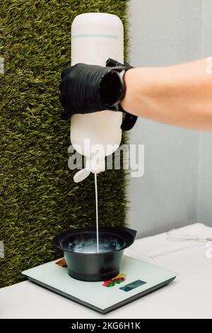 Ein Friseur gießt ein Oxidationsmittel ein. Der Vorbereitungsvorgang vor dem Färben der Haare Stockfoto