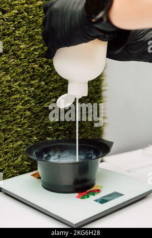 Ein Friseur gießt ein Oxidationsmittel ein. Der Vorbereitungsvorgang vor dem Färben der Haare Stockfoto