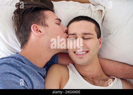 Der Morgen war wunderschön. Ein junges schwules Paar, das sich im Bett entspannt. Stockfoto
