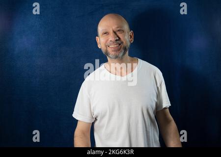 Das Porträt eines bärtigen kahlen glücklichen Mannes vor blauem Hintergrund Stockfoto
