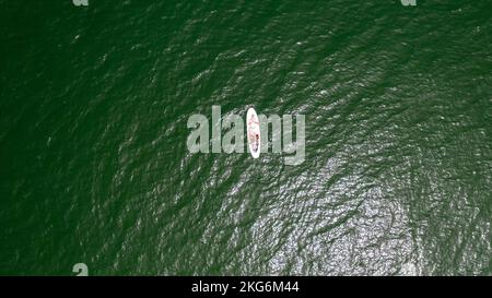 Drohnenaufnahme eines Surfers auf einem Surfbrett mitten im Ozean. Stockfoto