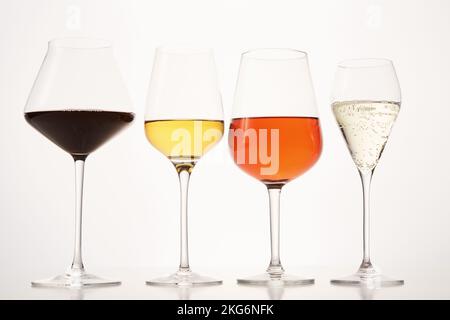 Rosafarbene, weiße, rote, prickelnde alkoholische Getränke in Weingläsern. Stockfoto