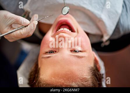 Keine Hohlräume hier. Hochwinkelige Aufnahme eines jungen Mädchens, das ihre Zähne von einem Zahnarzt untersuchen lässt. Stockfoto