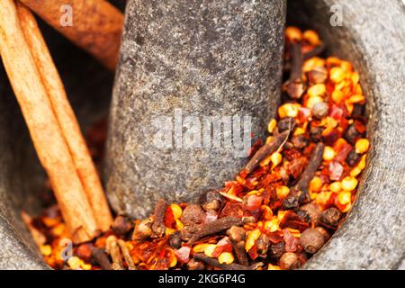 Es wird heiß. Mörser und Stößel mit Chilisamen im Inneren. Stockfoto