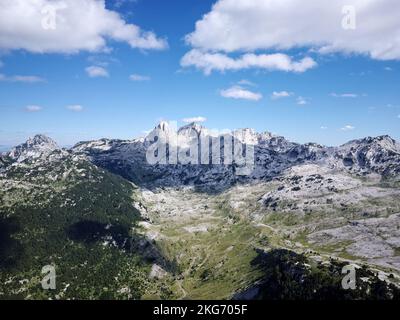 Luftdrohnen-Ansicht von verschiedenen Berggipfeln während eines schönen sonnigen Tages mit einem grünen Tal unten. Verbindung mit der Natur, Mehr Abenteuer im Leben Stockfoto